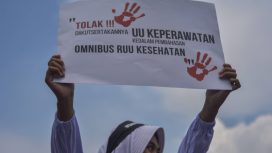 Seorang tenaga kesehatan membentangkan poster saat berunjuk rasa menolak RUU Omnibuslaw Kesehatan di depan Gedung Parlemen, Senayan, Jakarta, Senin (28/11/2022). Foto: Sulthony Hasanuddin/Antara Foto