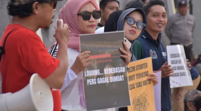 Jurnalis Sulteng di Palu membentangkan poster dalam aksi mimbar bebas menolak gugatan Menteri Pertanian terhadap Tempo yang dinilai mengancam kebebasan pers, Minggu (16/11/2025). Foto: Istimewa