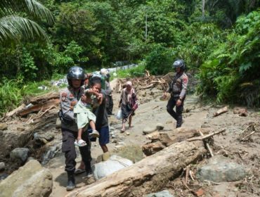Petugas kepolisian membantu evakuasi warga, termasuk anak-anak, melintasi jalur terdampak banjir dan longsor di wilayah Donggala. Foto: Tim Gubernur Sulteng 