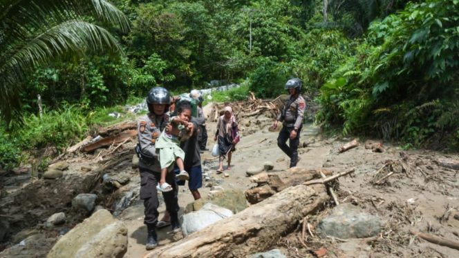 
 Petugas kepolisian membantu evakuasi warga, termasuk anak-anak, melintasi jalur terdampak banjir dan longsor di wilayah Donggala. Foto: Tim Gubernur Sulteng 