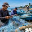 Ilustrasi nelayan memperbaiki pukat di kawasan pesisir. Foto: PPID/AI
